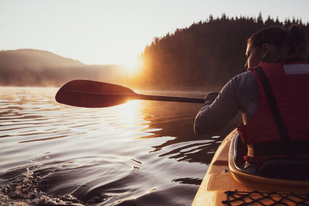 Woman kayaking at sunrise after a shoulder injury while reflecting on chronic pain management and natural healing strategies.