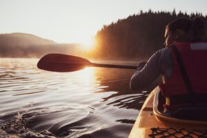Woman kayaking at sunrise after a shoulder injury while reflecting on chronic pain management and natural healing strategies.